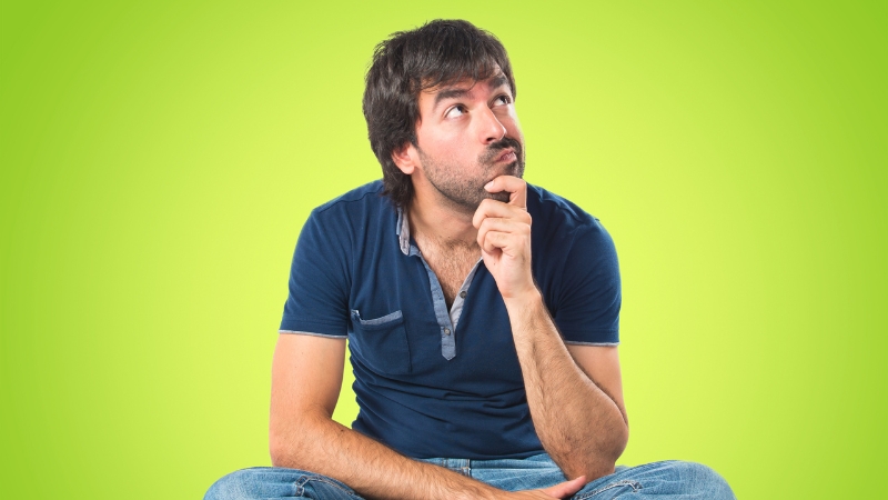 Muškarac sedi i zamišljeno gleda nagore, dok je iza njega svetlo zelena pozadina